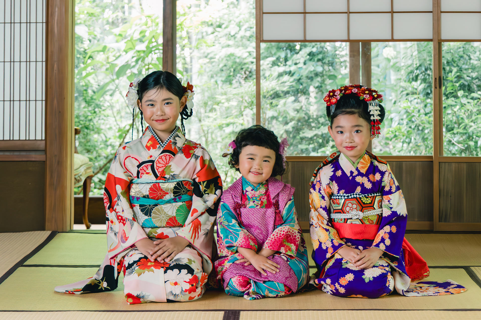 七五三用アンティーク着物を着た女の子三人が和室で正座し笑顔を見せる撮影シーン