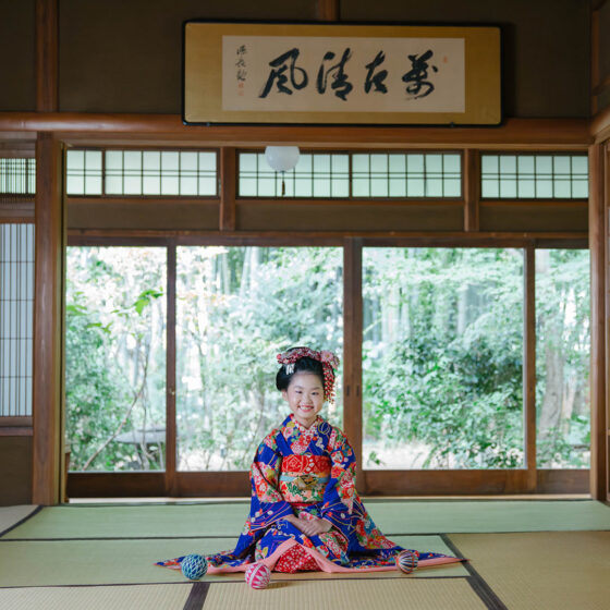 アンティーク着物を着た女の子が和室で正座して微笑んでいる